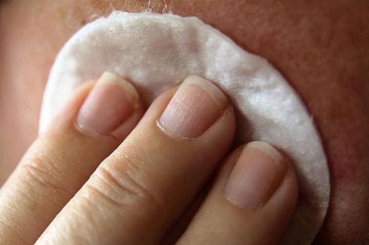 aplicación de tóner facial con aceite de bergamota con un algodón